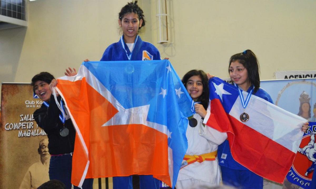 Rocio Ledesma stands on top of the podium whilst holding the flag from her province.