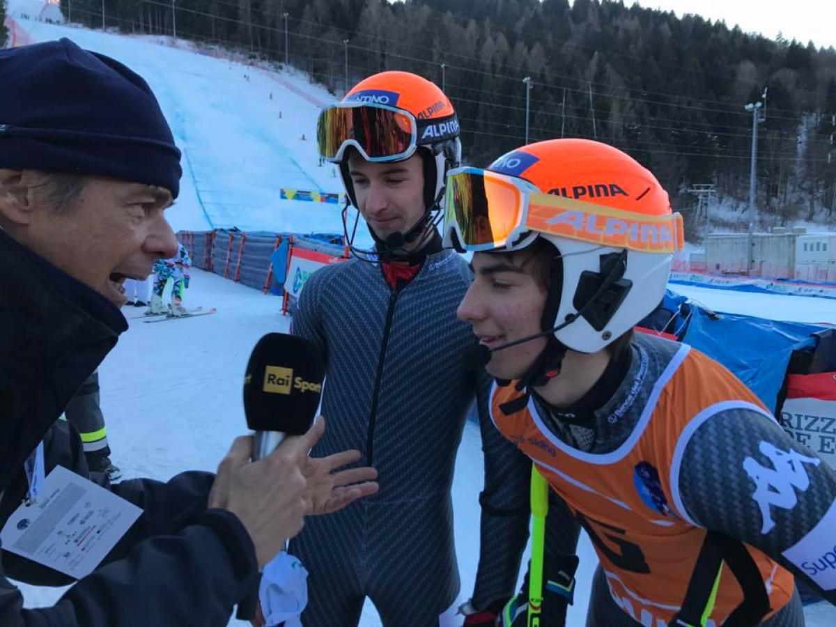 A visually impaired skier and his guide are interviewed