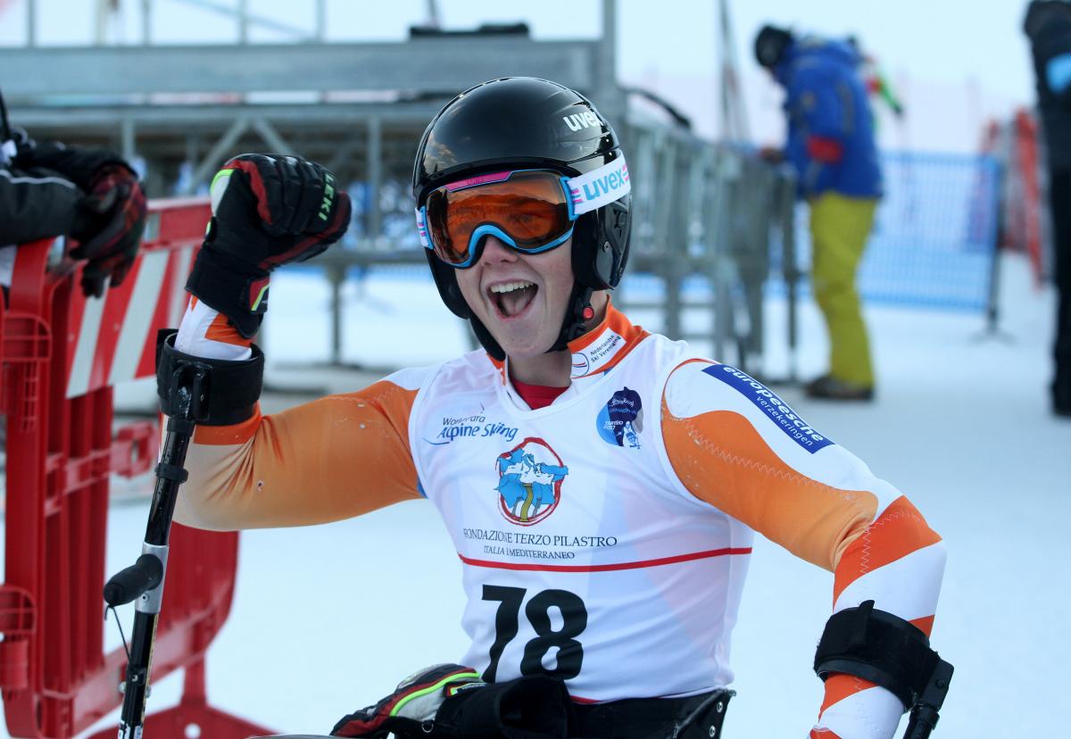 Man in ski helmet and goggles smiles in a sit ski