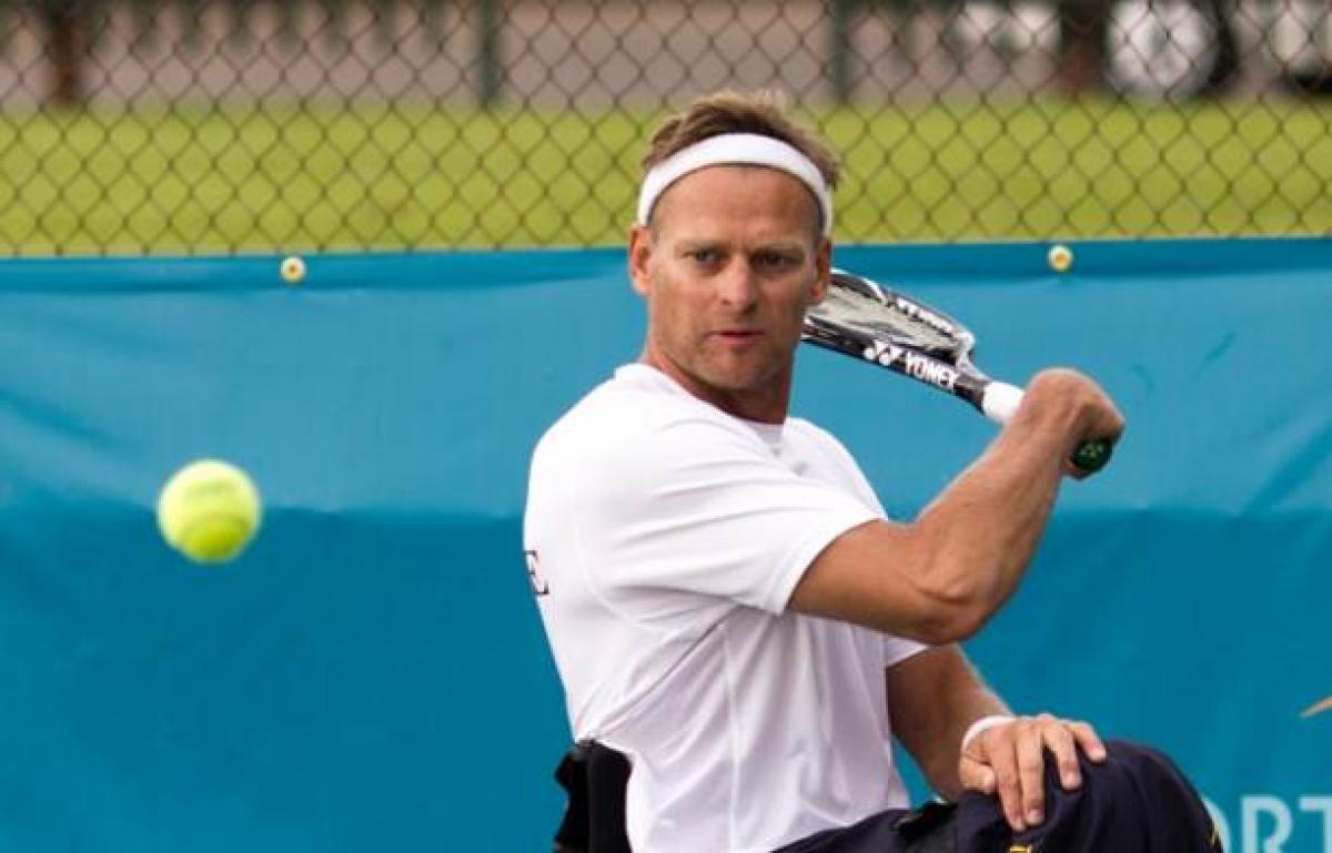 A picture of a man in a wheelchair playing a backhand