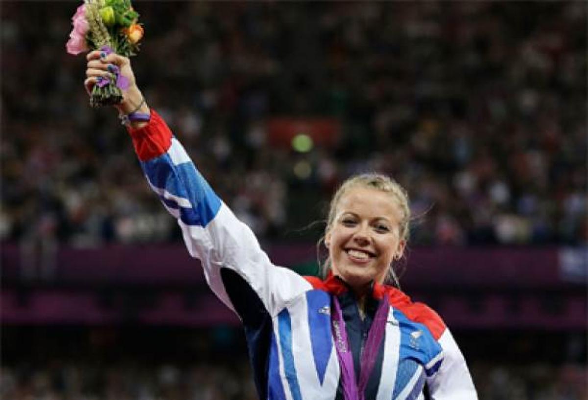 A picture of a woman showing her gold medal during a medal ceremony