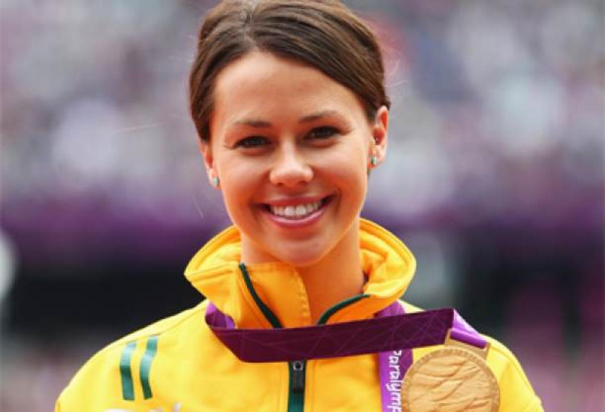 A picture of a woman showing her gold medal hanging around her neck