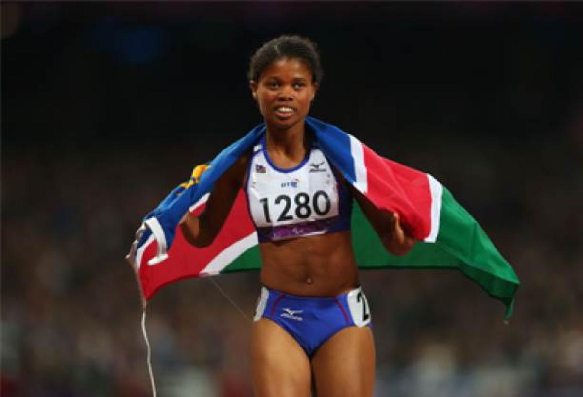 A picture of a woman on a track with the Namibian flag around her neck