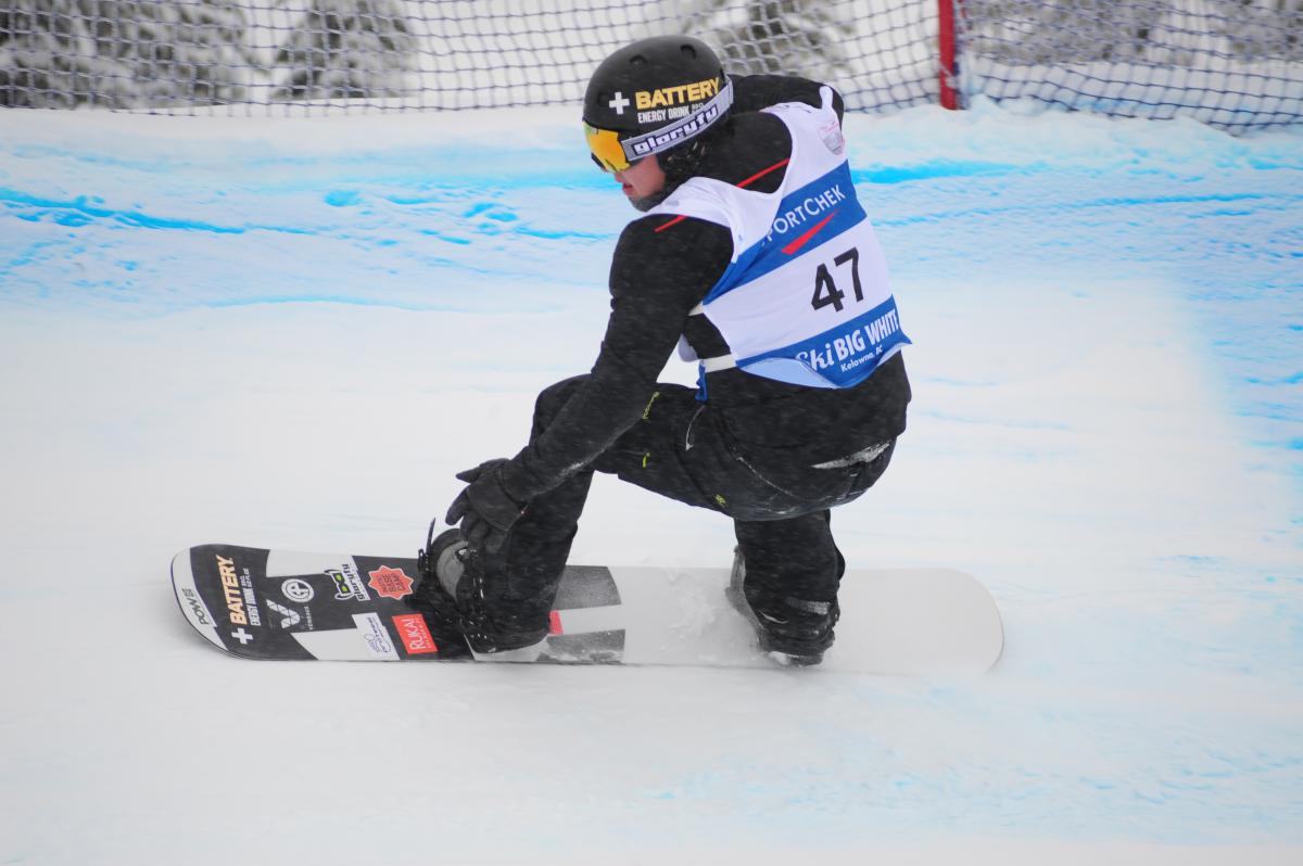 Man on snowboard rides down a snowboard-cross course.