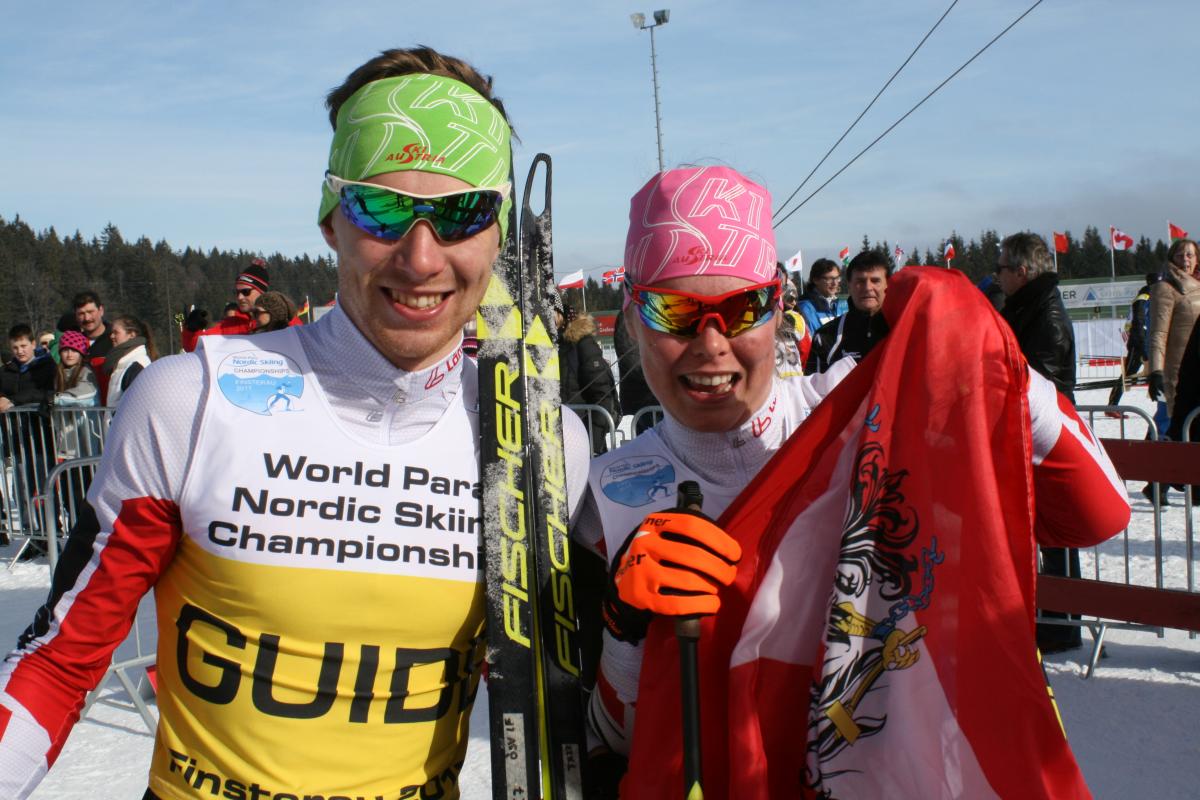 Two cross-country skiers with an Austrian flag