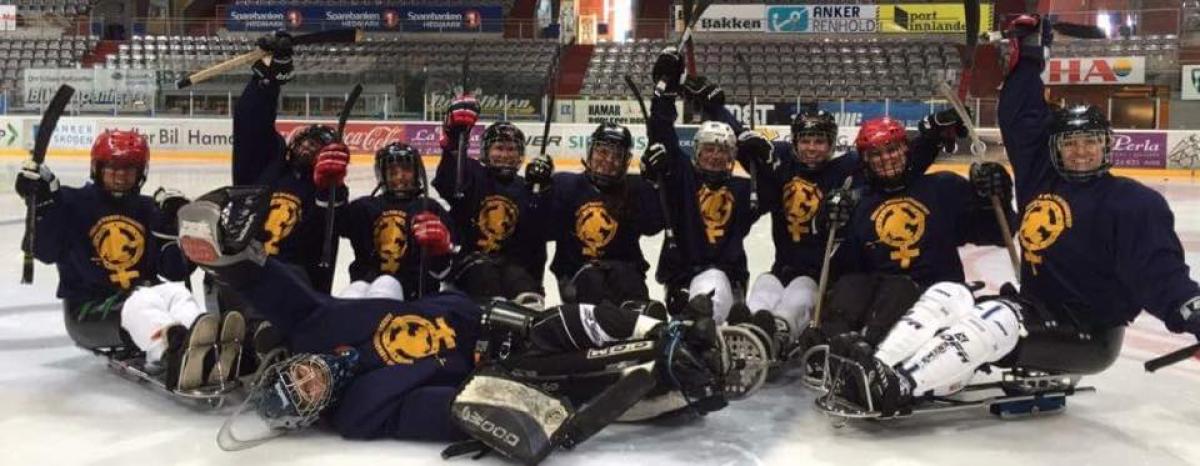 Group of female sledge hockey players pose for a photo