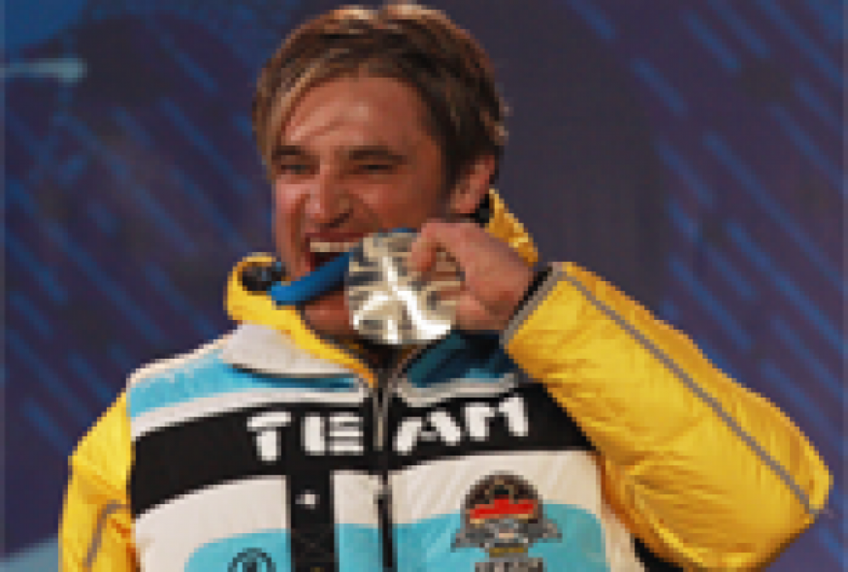 A picture of a man beating his silver medal during a medal ceremony