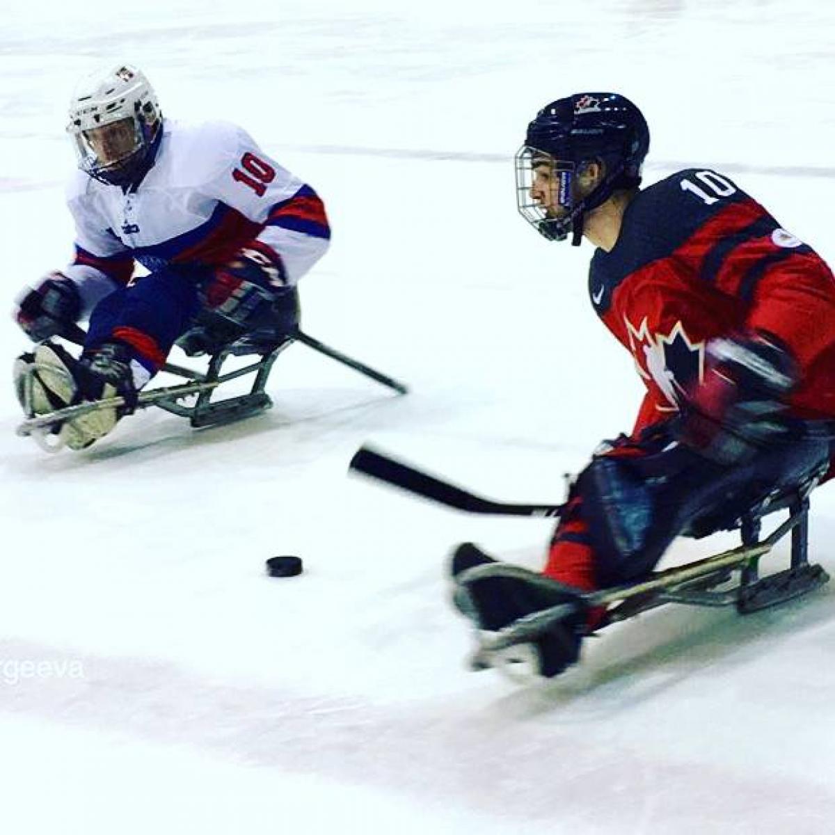 Two Para ice hockey players duel on the ice