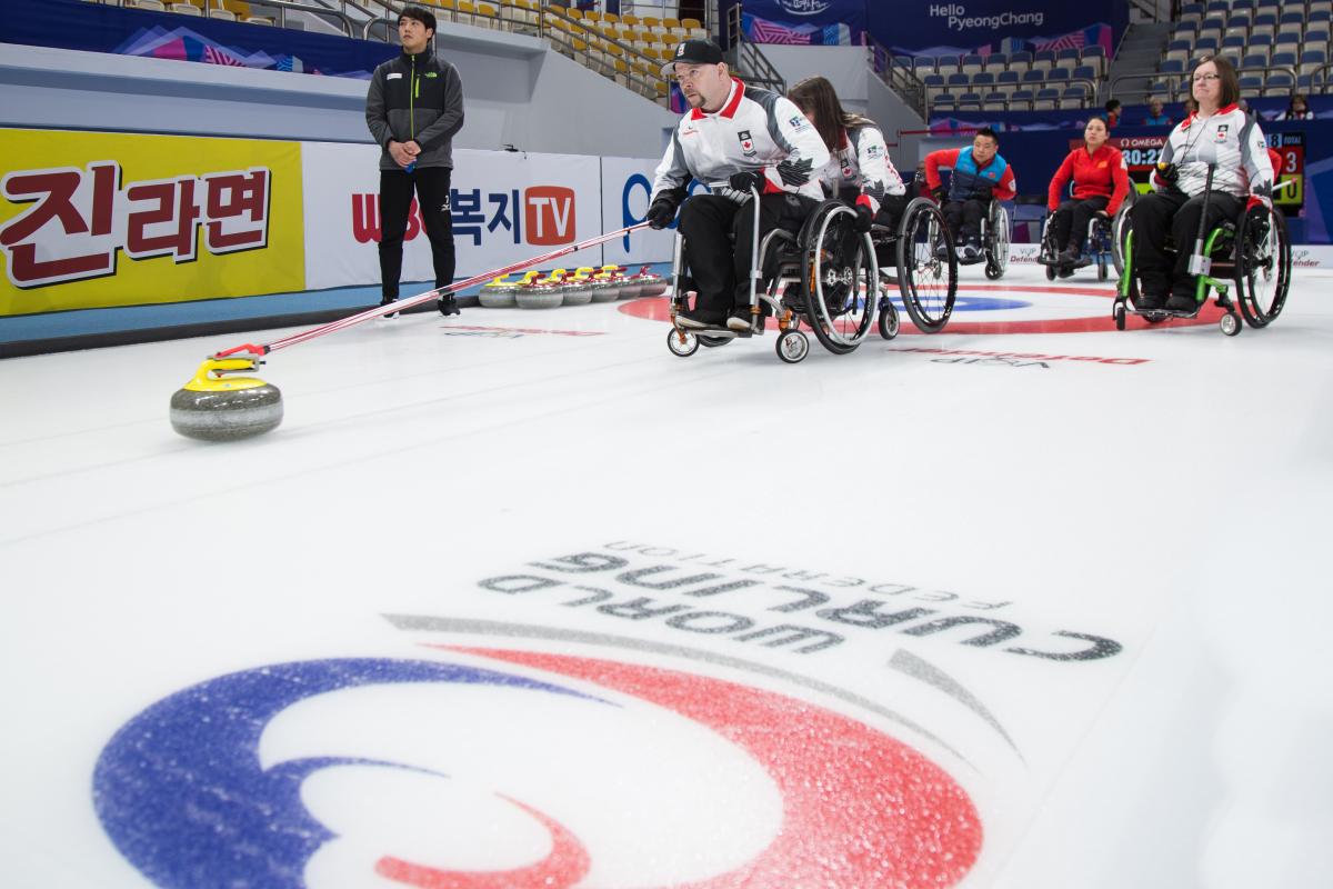 People in wheelchairs on ice rink, curling