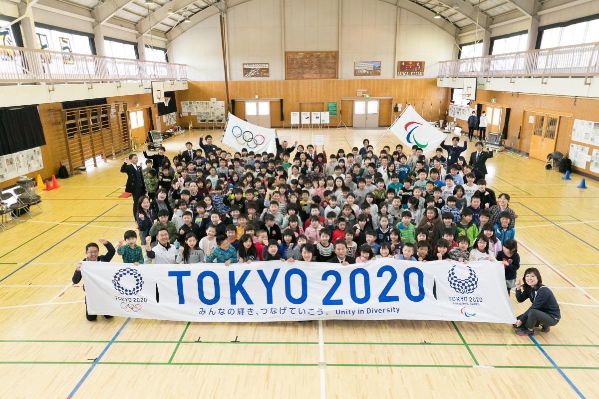 Group picture of many people gathering around a banner