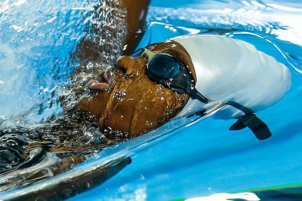 Athlete in water with goggles competes in backstroke 