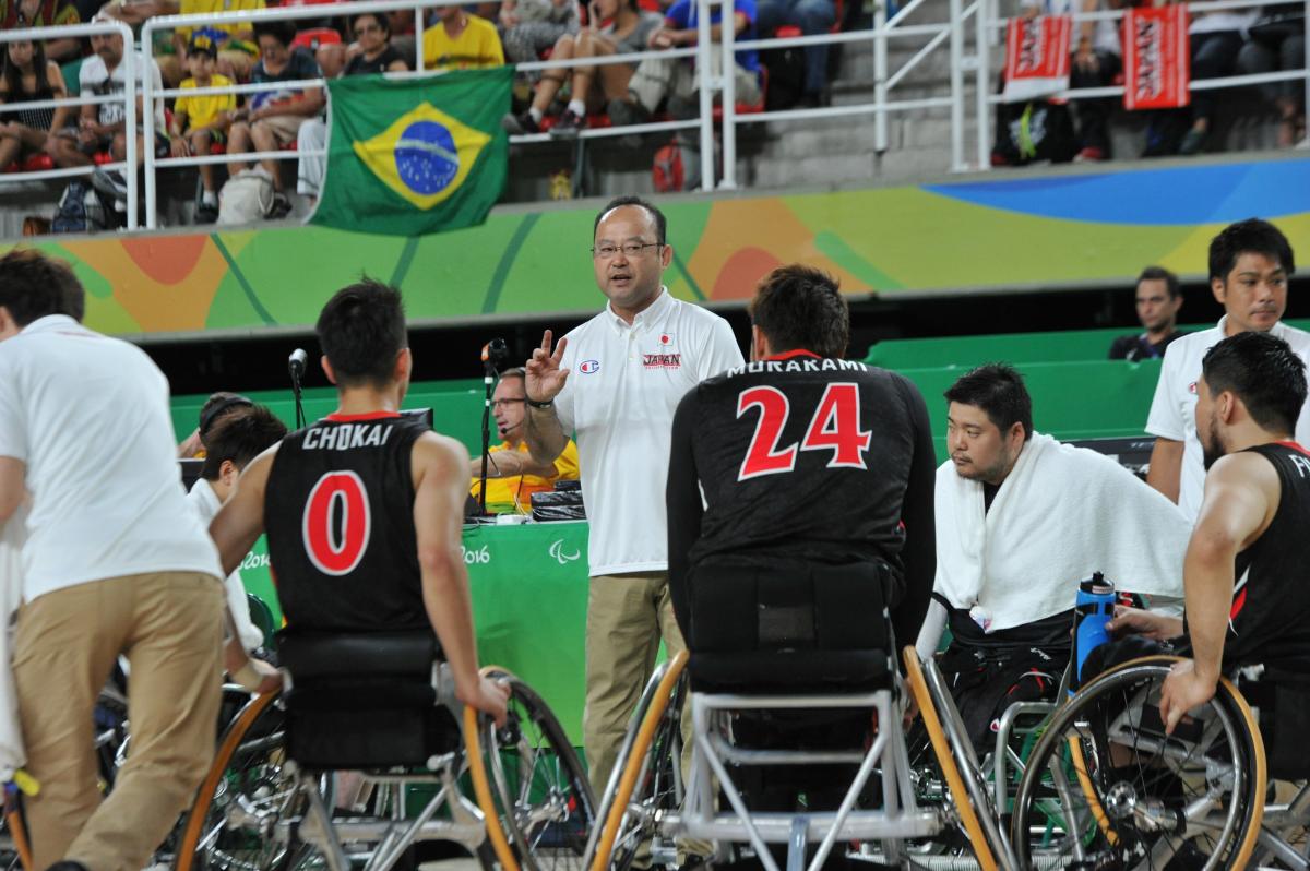 Coach surrounded by his men's wheelchair basketball team giving instuctions 