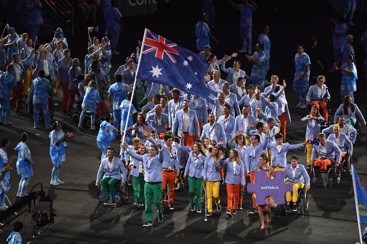 A group of Para athletes march into a stadium with one athlete holding the Australian flag during the Rio 2016 Opening Ceremony