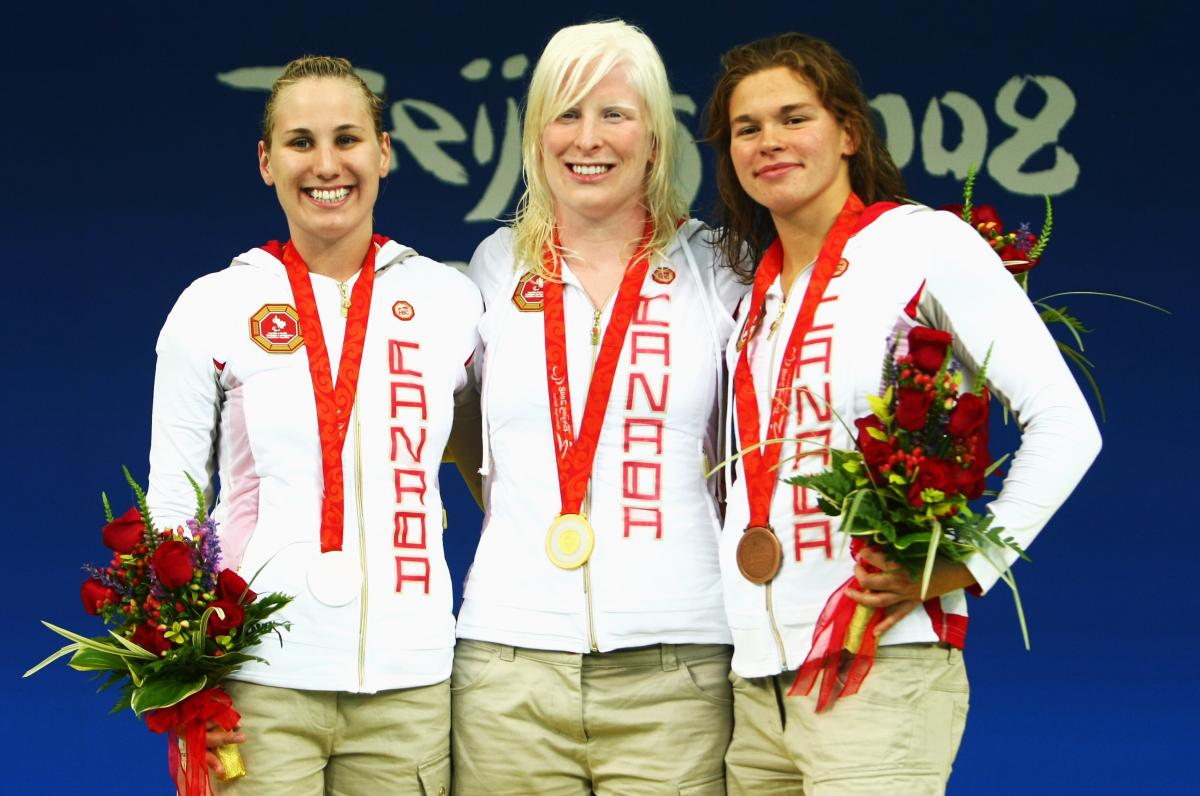 Three female swimmers pose for a photo