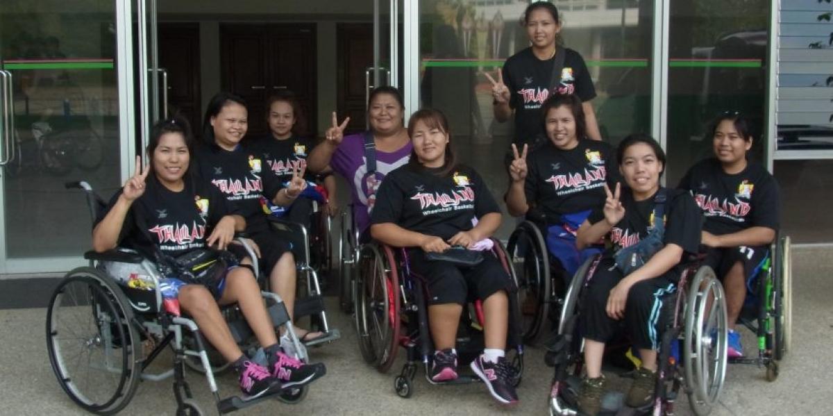 Group of Asian women's wheelchair basketball players pose 