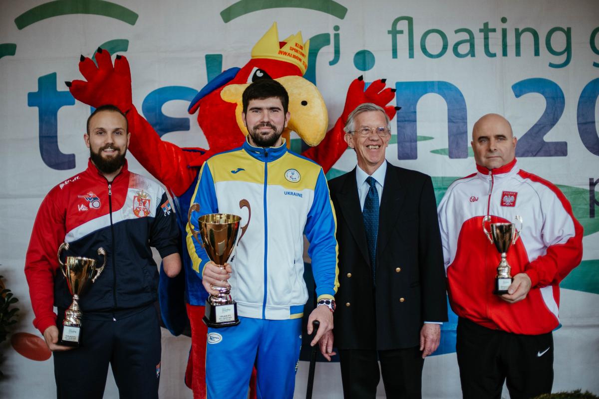 Three men holding trophies 