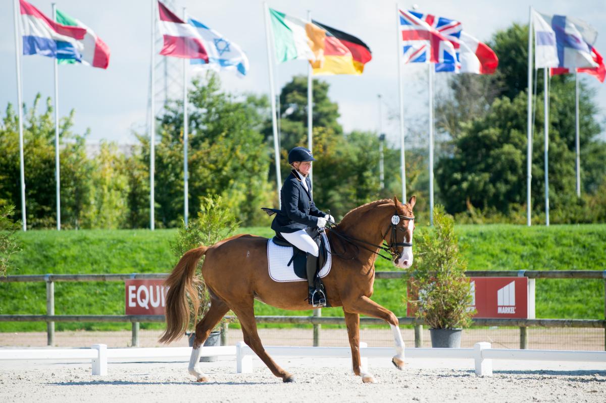 Woman riding a horse with various nation's flags in the background