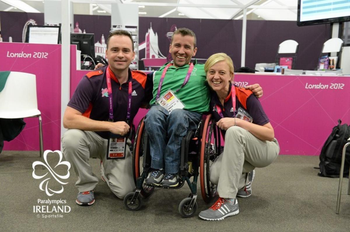 Man in wheelchair between two people posing for photo