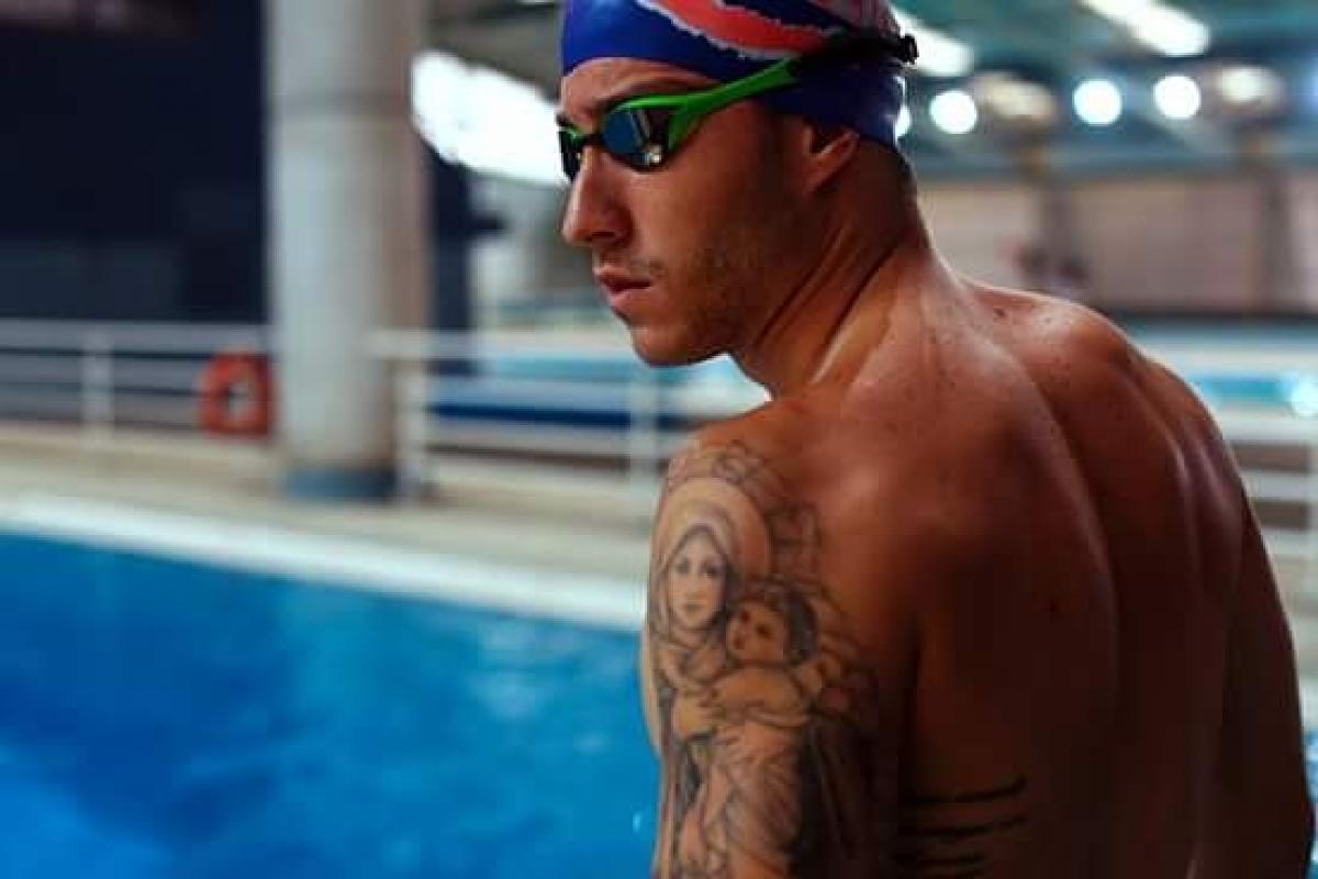 Lucas Poggi male swimmer poses at the side of the pool
