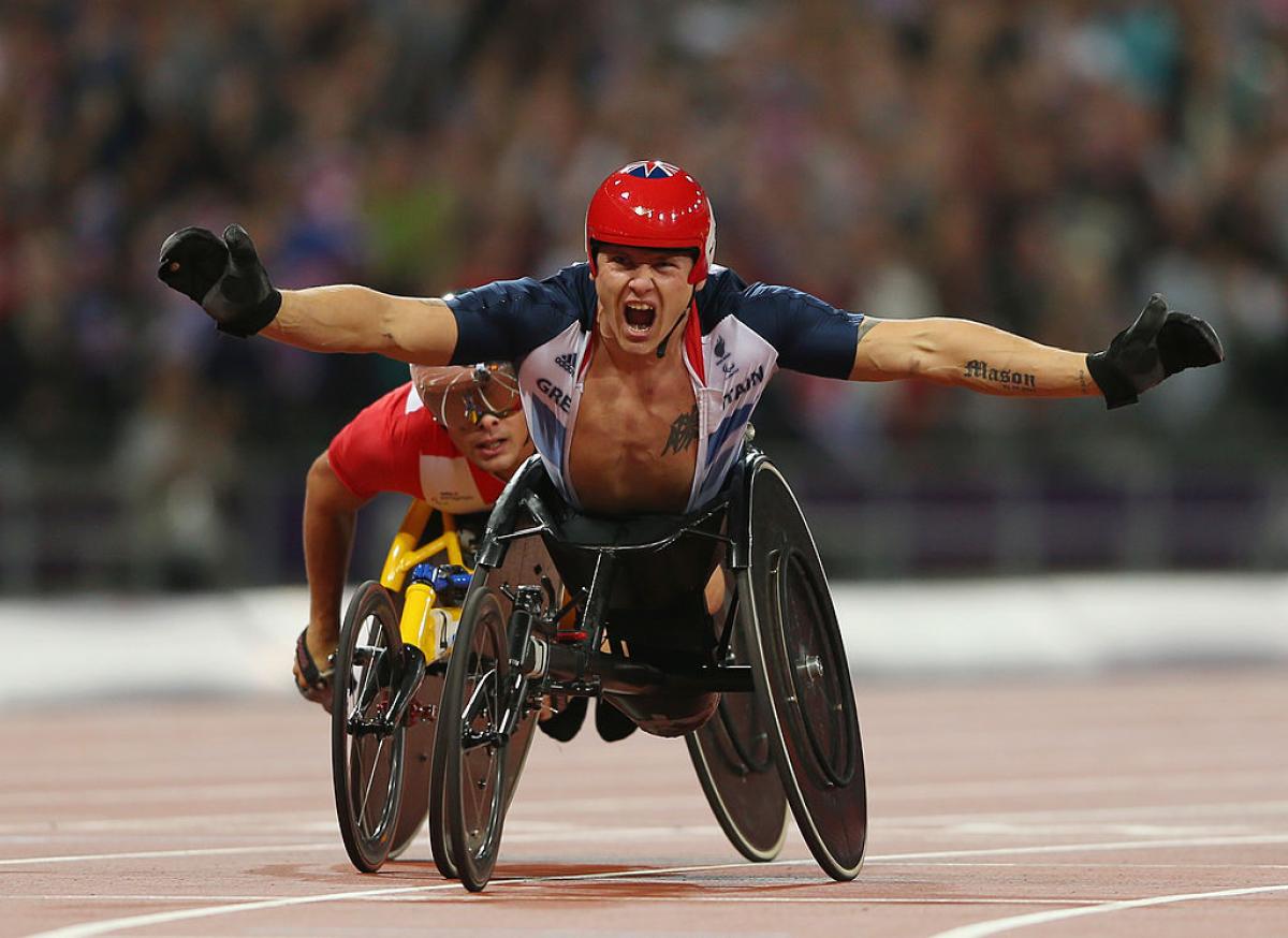 Wheelchair racer celebrates crossing finish line