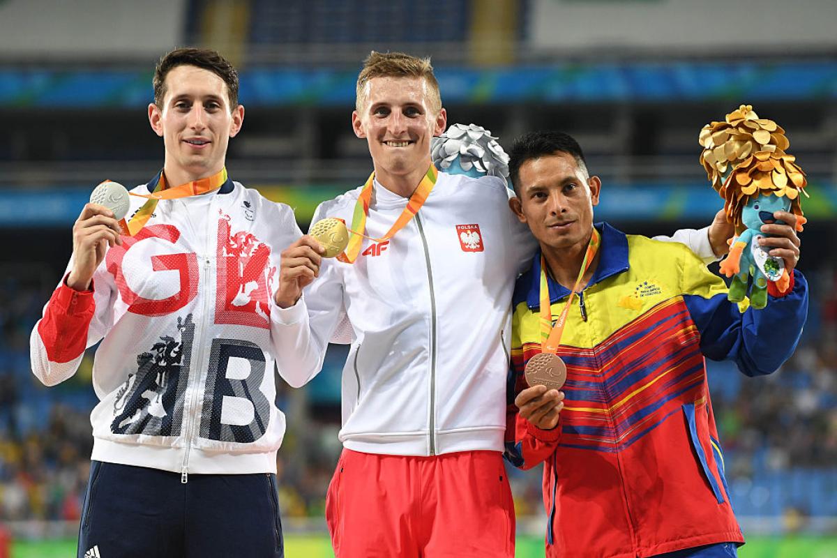 three men with medals on the podium