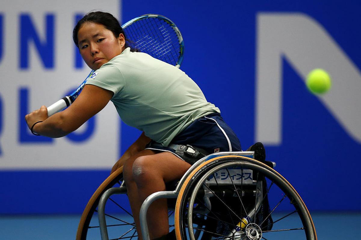 female wheelchair tennis player hits a backhand