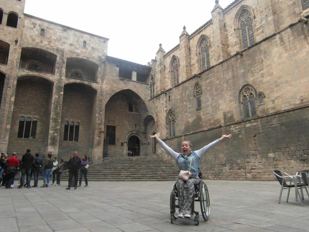 woman in wheelchair smiling with arms outstretched
