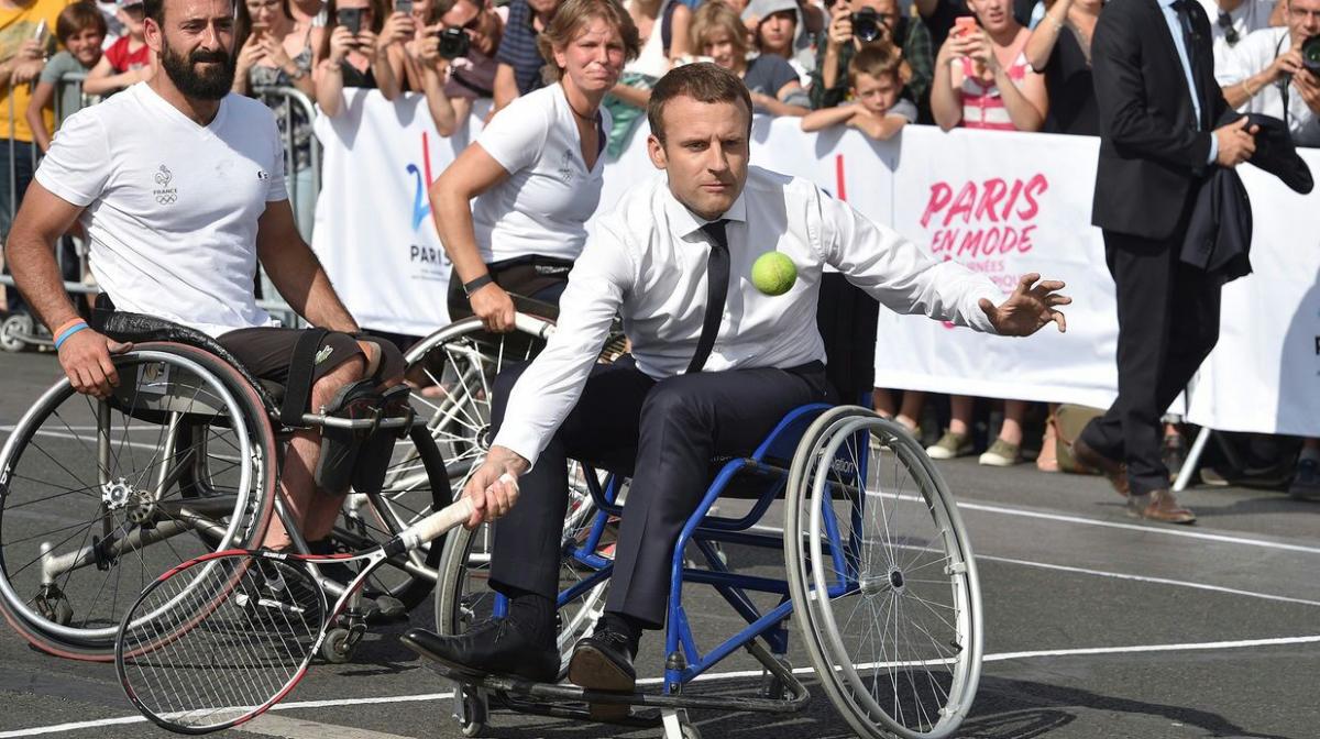 man in suit plays tennis in wheelchair