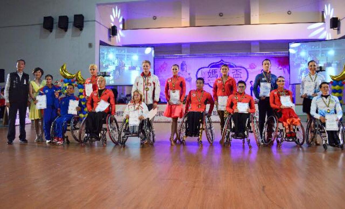 A row of men and women in wheelchairs with competition certificates