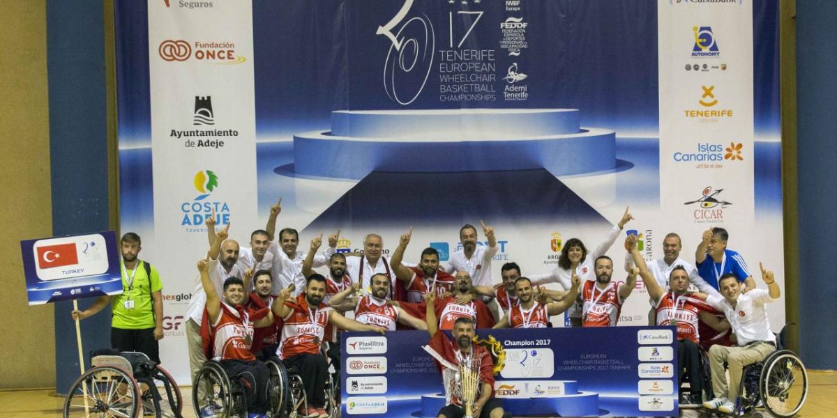 a group of men in wheelchairs celebrate with their trophy