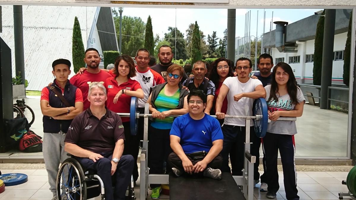 A group of men and women standing and in wheelchairs smile for the camera