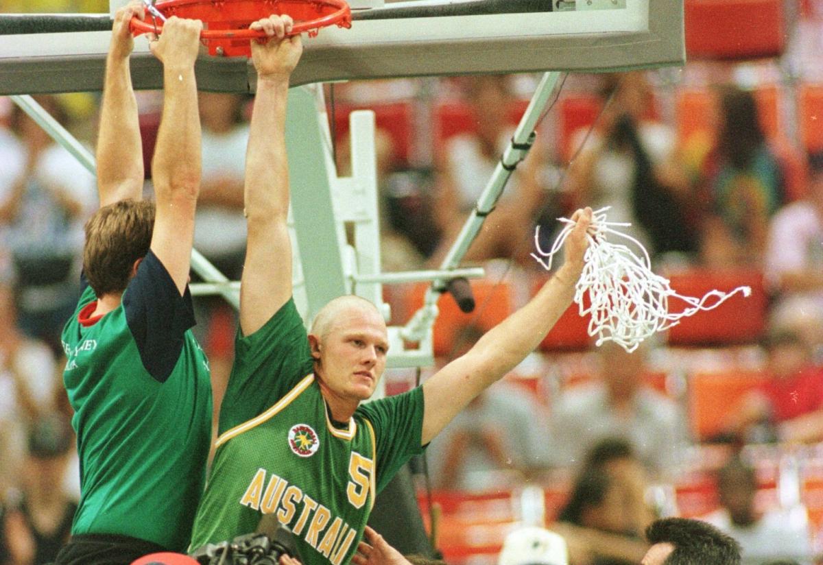 A man hangs off a basketball hoop