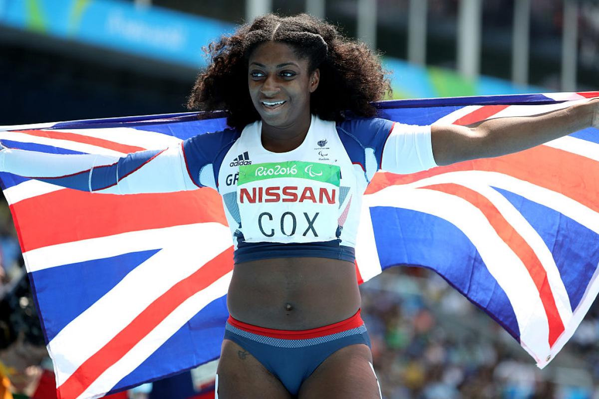 a female para athlete holds up a British flag