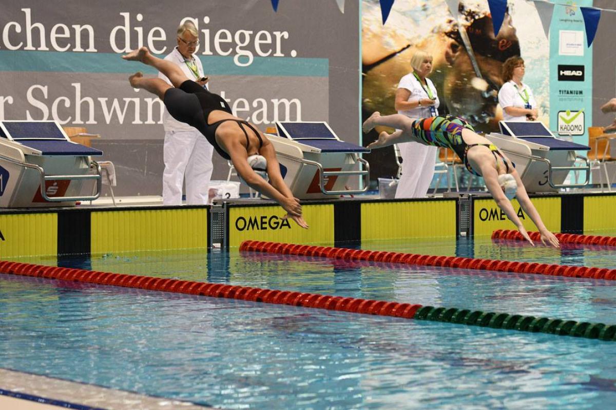 Berlin World Series two female swimmers jump into the pool at the start of a race