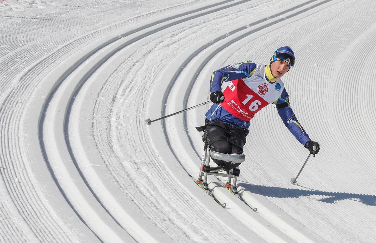 a sitting biathlete skies down a slope