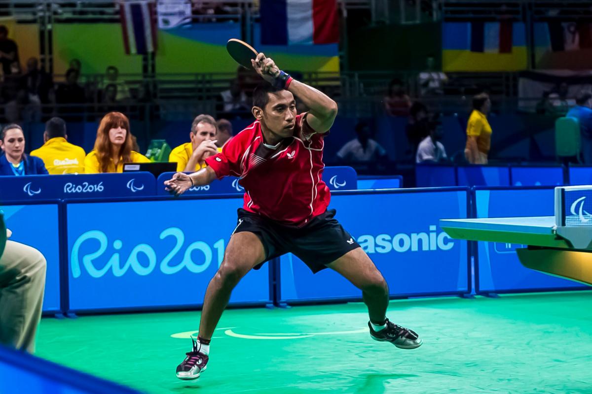 a para table tennis player hits the ball across the net