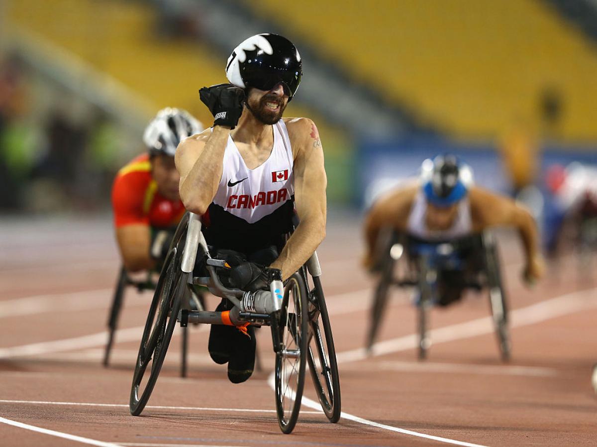 a wheelchair racer pumps his fist after crossing the line