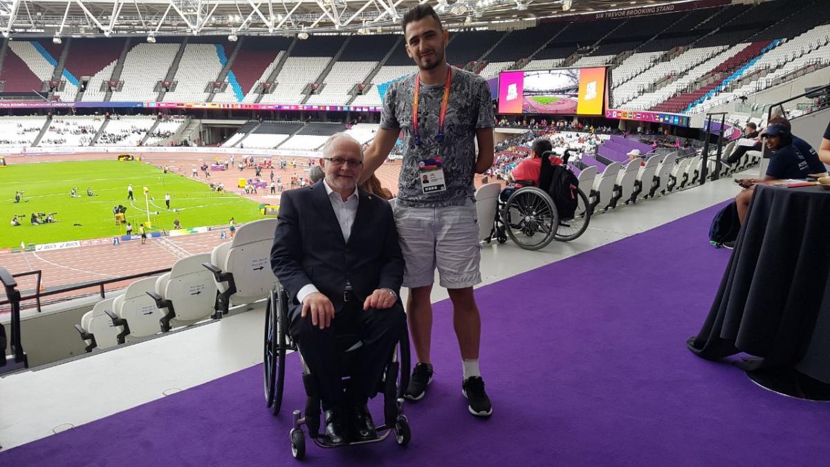 a para athlete stands beside a man in a wheelchair