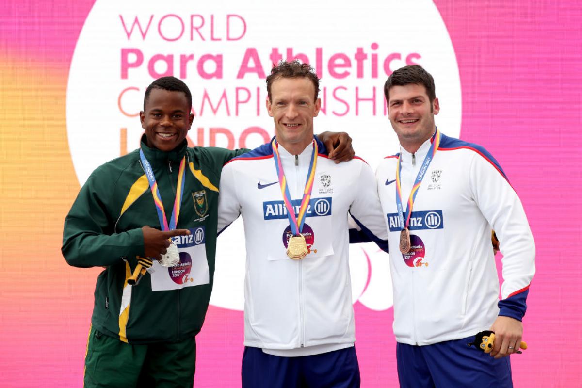 three men stand on the podium with their medals