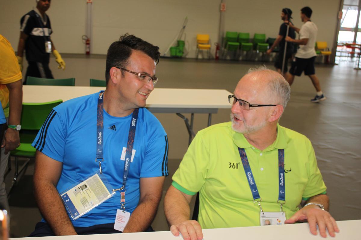 two men chat at a table