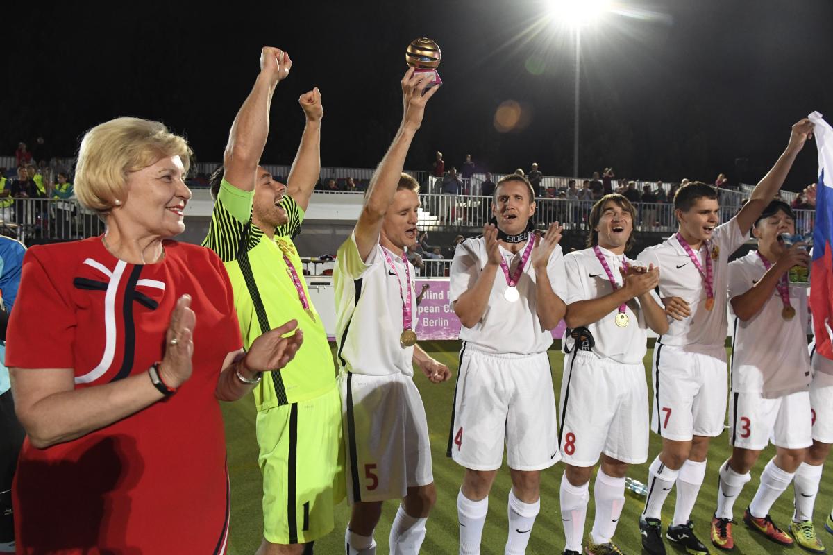 a group of male blind footballers raise their arms in celebration