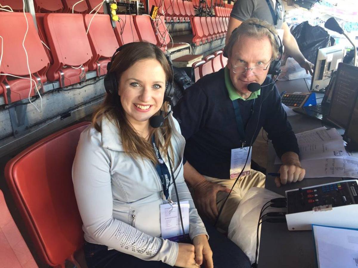 a man and a woman sit in a commentary box