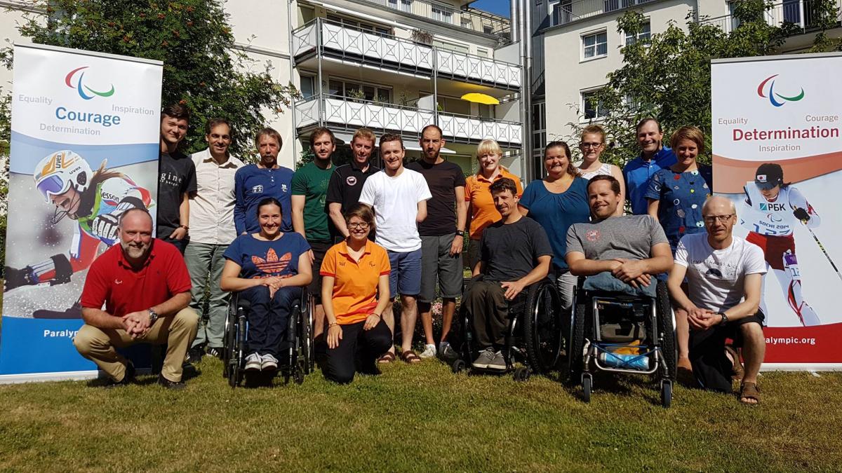 Alpine skiing experts meeting a group of officials and Para athletes smile for the camera