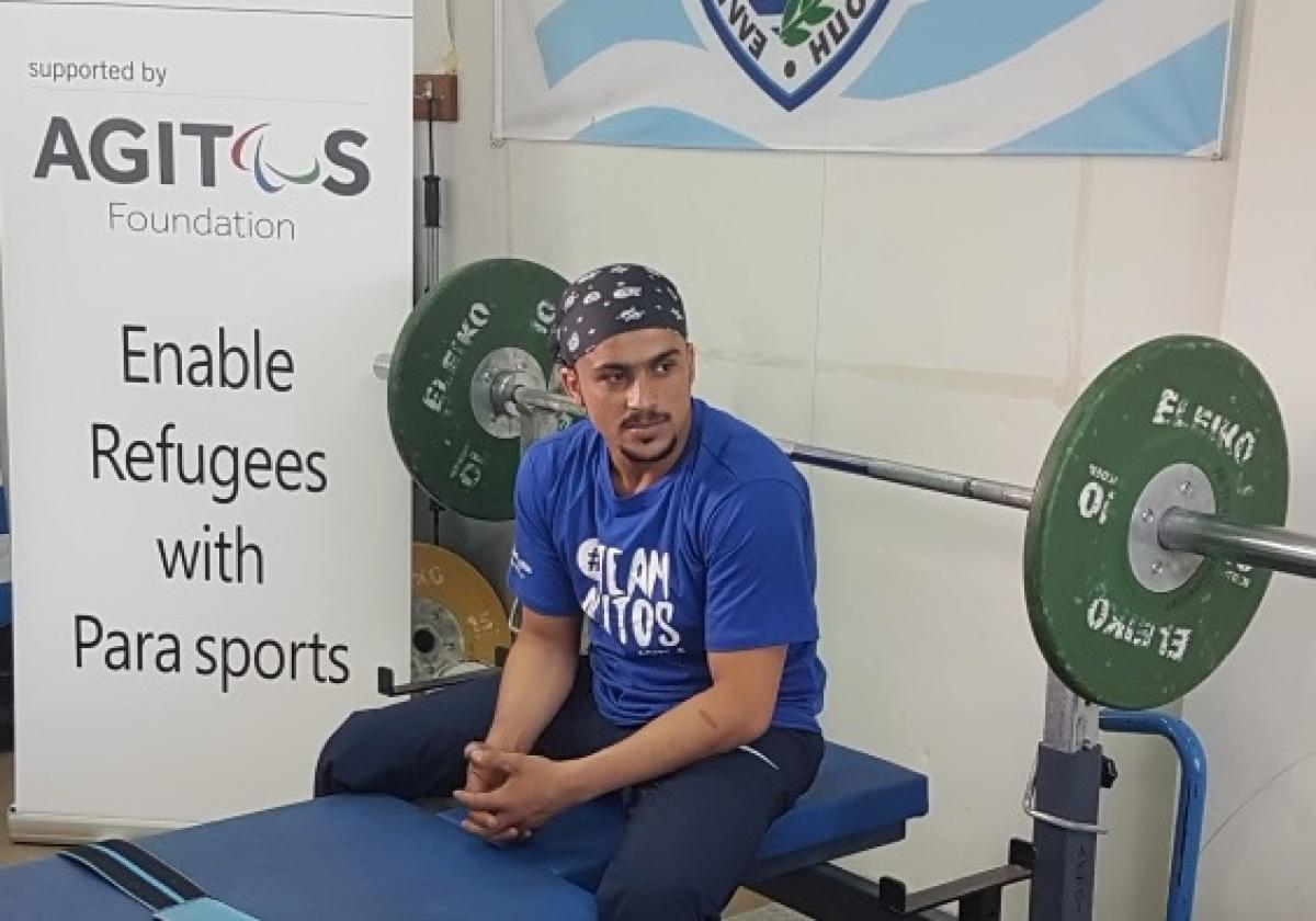 a male Para powerlifter sits on his bench