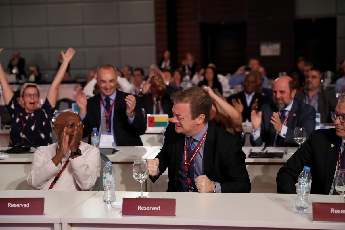 a man celebrates while people punch the air behind him