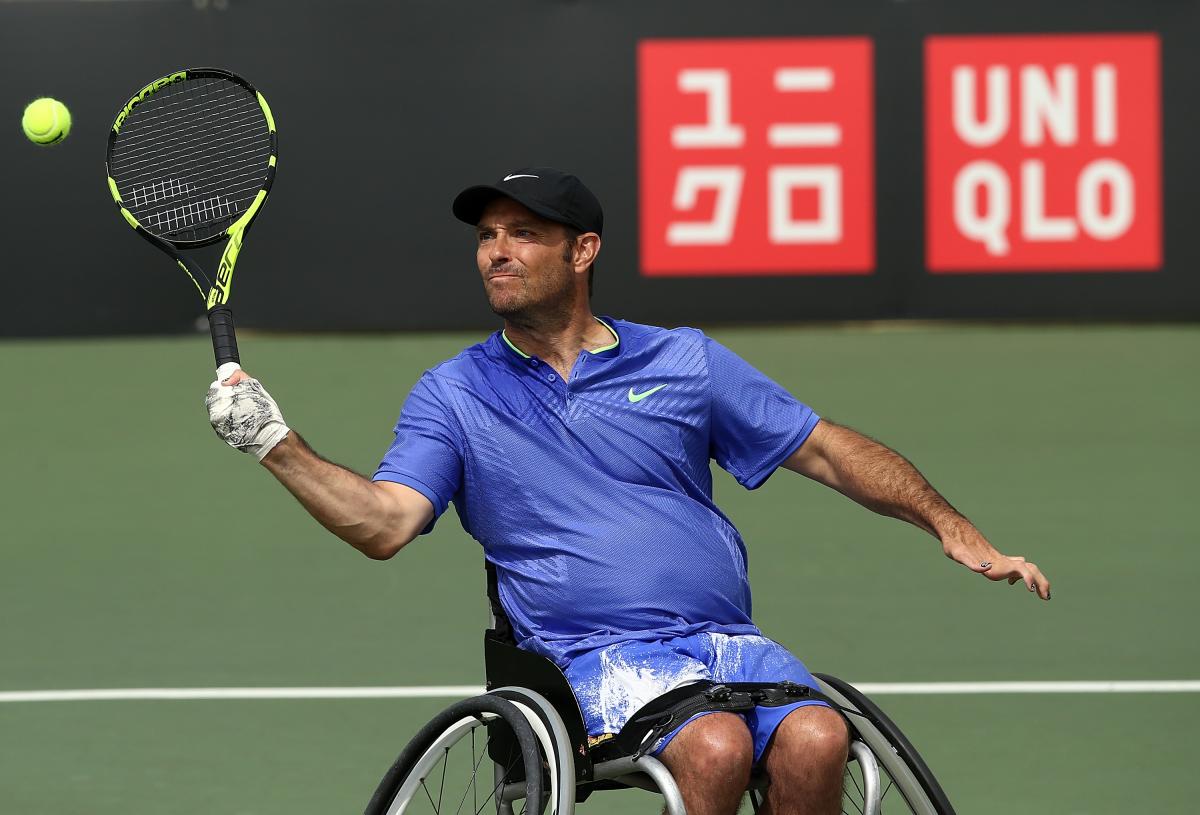 a male wheelchair tennis player hits a forehand