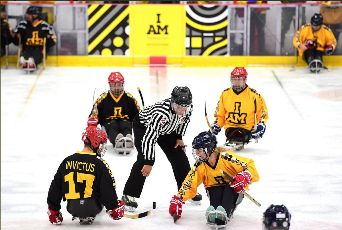 a group of Para ice hockey players take instruction from a referee