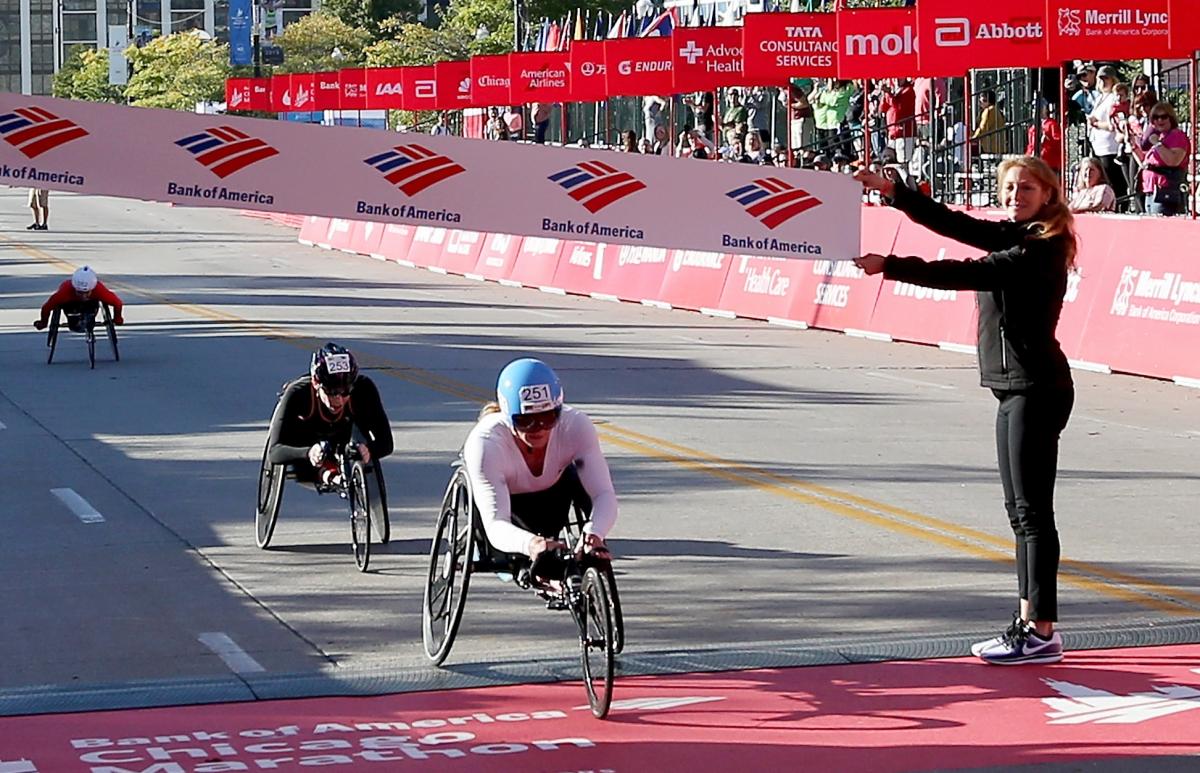a female wheelchair racer crosses the finish line