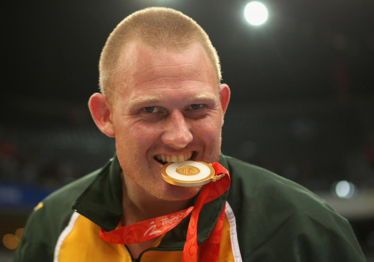 a male Para athlete bites his medal