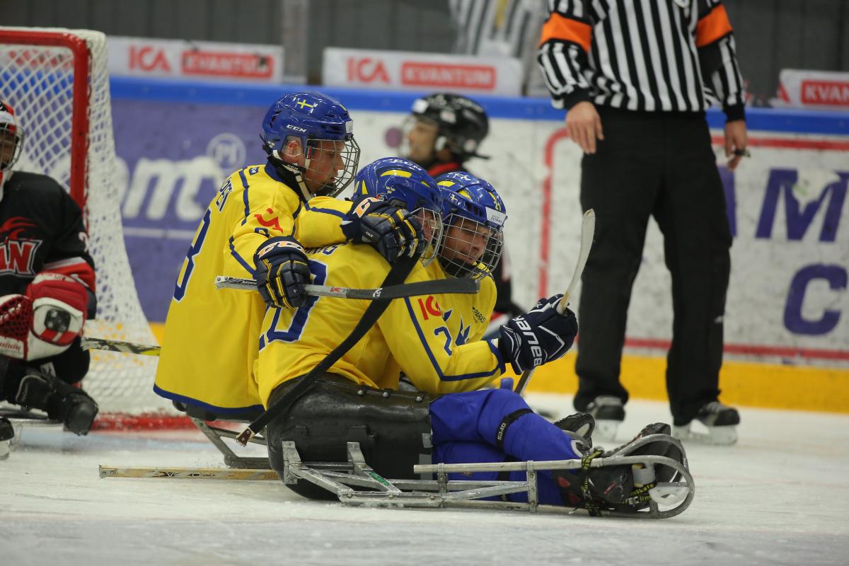 a group of Para ice hockey players celebrate on the ice